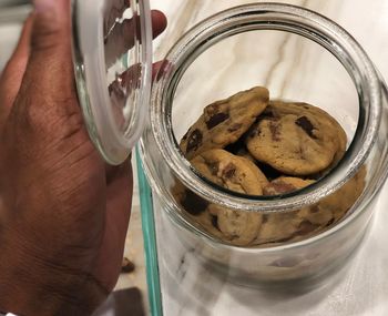 Close-up of hand holding ice cream in glass jar on table