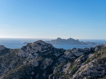 Scenic view of sea and mountains against blue sky