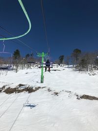 Ski lift over snow covered field against sky