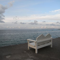 Empty chair on beach against sky