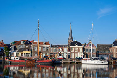 An old flat bottomed and a modern sailing ship in the port of lemmer on the ijsselmeer in holland