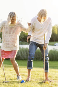 Happy friends playing croquet on field