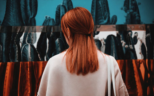 Rear view of woman with ginger hair standing in store