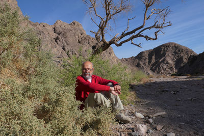 Senior man sitting on rock against mountain