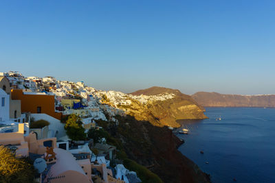 Townscape by sea against clear blue sky