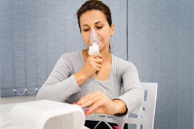 Woman holding nebulizer while sitting at table