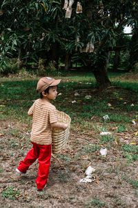 Rear view of boy carrying basket at farm