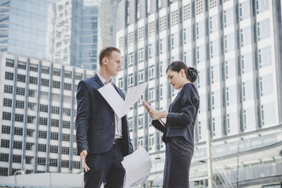 Business people discussing while standing against building