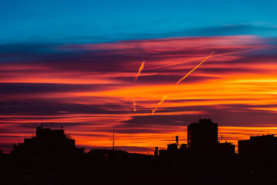 Silhouette buildings against dramatic sky during sunset