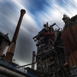 Low angle view of industry against sky in city