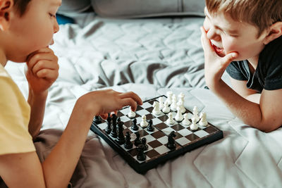 Boy playing with baby relaxing on bed