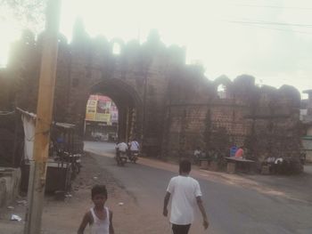 Rear view of people walking on street in city