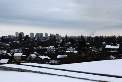 Houses and snow covered cityscape against sky