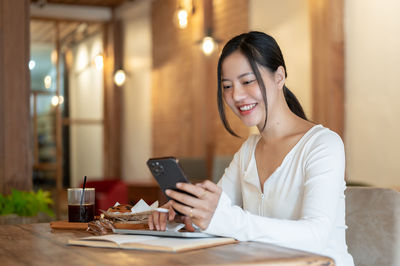 Young woman using mobile phone while sitting at home