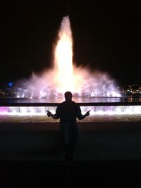 Rear view of silhouette man against illuminated sky at night