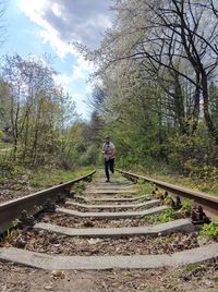 Rear view of man walking on railroad track