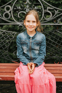 Portrait happy smiling candid eight year old kid girl face sits on bench in nature. prepubertal age