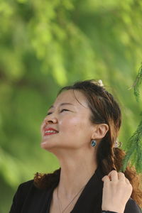 Smiling woman looking away against plants