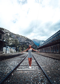 Full length of woman standing on railroad tracks against sky