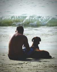 Rear view of man sitting on beach