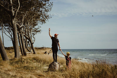 Full length of men on field by sea against sky