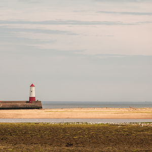 Lighthouse by sea against sky