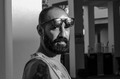 Close-up portrait of mid adult bearded man wearing sunglasses against building