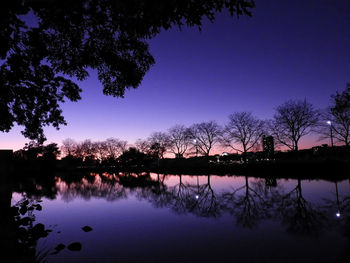 Reflection of silhouette trees in lake against sky