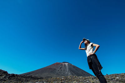 Low angle view of woman standing against clear blue sky