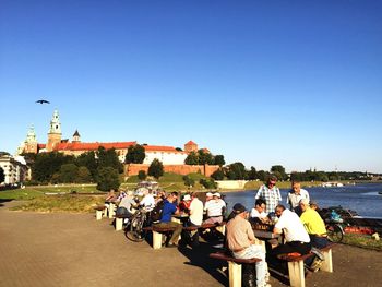 People by tables against clear blue sky