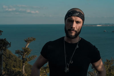 Portrait of fashionable man standing against sea