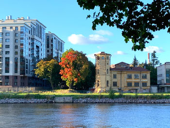 Buildings by river against sky in city