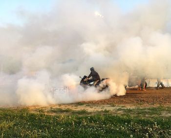 Man emitting smoke through motorcycle on field