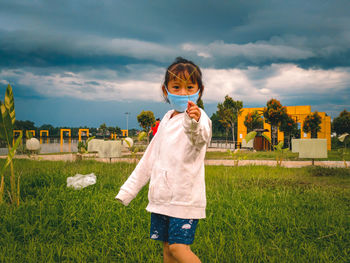 Portrait of young woman standing on grassy field