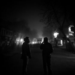 Rear view of silhouette people walking on illuminated street at night