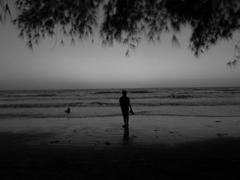 Silhouette man on beach against sky