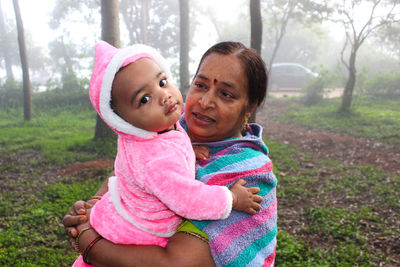 Grandmother holding cute grandson while standing outdoors