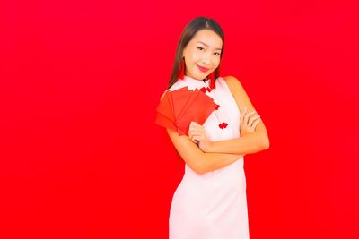 Portrait of a smiling young woman against red background