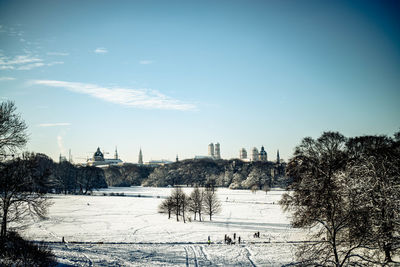 Snow covered field by buildings against sky