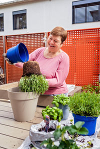 Portrait of young woman holding potted plant