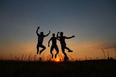 Silhouette of people jumping at sunset