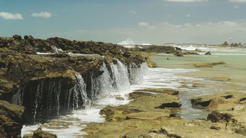 Scenic view of waterfall against sky