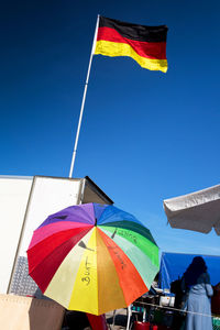 Low angle view of flags against clear blue sky