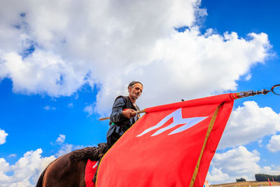 Low angle view of man with red umbrella standing against sky