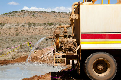 Truck pouring water on field against mountain