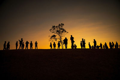 Large number of people standing on hill top against beautiful sun rising sky