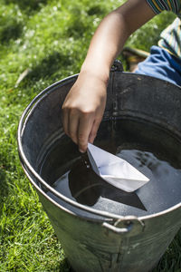 Midsection of child holding paper boat in water