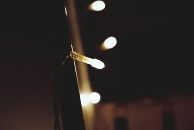 Low angle view of illuminated light bulb against sky at night