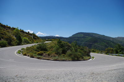 Road amidst mountains against clear blue sky
