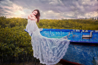 Beautiful young woman standing in water against sky